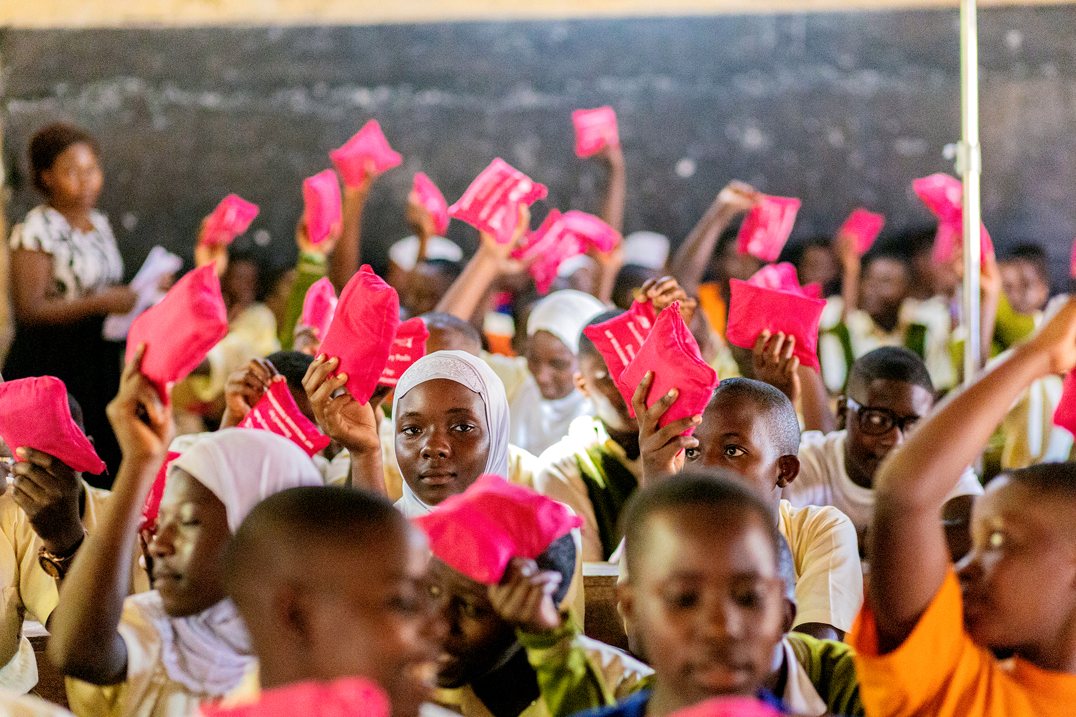 Girls in a classroom holding up reusable sanitary pads